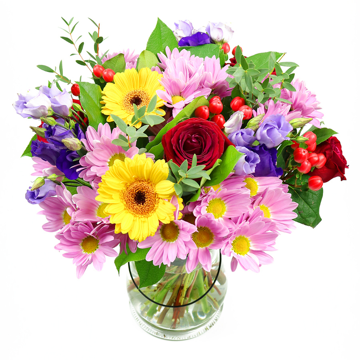 In this image, a striking mixed bouquet stands proudly in a simple, clear glass vase, set before a pure white background that lets the colours glow. At the core of the arrangement, rich crimson roses unfold in velvety spirals, giving the design a classic, heartfelt tone. Nearby, two sunny yellow gerbera daisies with dark brown-orange centres beam outward, their flat, daisy-like faces infusing the whole bouquet with a joyful, optimistic character. Encircling these main blooms, clusters of soft pink daisies or chrysanthemums stretch their many slim petals outwards, forming a generous collar of colour and softly blurring the edges between each individual stem. Threaded among the pinks and yellows, purple and lavender lisianthus blooms add contrast and depth; their bell-shaped flowers and gently curling petals introduce a cool, elegant counterpoint that keeps the arrangement from feeling too sweet. Small sprays of bright red hypericum berries pop up like tiny lanterns, adding a contemporary texture and a subtle hint of playfulness. The flowers are nestled within a rich framework of greenery, mixing broad, darker leaves with finer, paler foliage, giving the bouquet a natural, almost garden-picked feel, as if it had been gathered near the green spaces around Chestnuts Park in South Tottenham. Through the transparent glass, neatly trimmed stems stand in clear water, revealing the structured underlayer that supports the loose, abundant top. The overall effect is one of generous celebration and warmth, suitable for birthdays, thank-yous, or simply brightening a kitchen table in a South Tottenham home, with each element carefully placed to create harmony from every viewing angle.