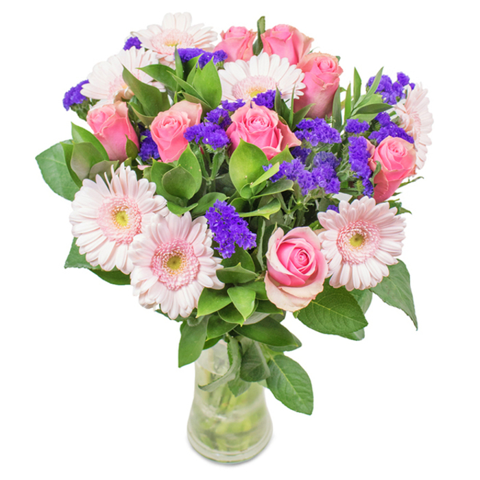 Expertly arranged by a South Tottenham florist, this bouquet is a vibrant symphony of pinks and purples, elegantly presented in a clear glass vase with stems visible through crystal water. The centrepiece features approximately seven to nine pink roses, their petals at various stages from tight bud to unfurling bloom, forming a spiral that draws the eye. Nestled among them are five to seven soft pink Gerbera daisies, their broad, pastel faces and nearly white centres imparting a gentle radiance. Threads of vivid purple statice weave between the roses and gerberas, offering striking colour contrast and intriguing texture-like a flourish of wildflowers from the edges of Chestnuts Park. Deep green foliage underpins the arrangement, adding volume and the fresh aroma of newly cut stems, much like the scent of garden plots around South Tottenham community allotments. The see-through vase and minimalist styling speak to both sophistication and approachability, making the bouquet ideal for milestone anniversaries, birthday surprises, or simply bringing a burst of cheer to a home office in West Green. This arrangement, available for local delivery throughout South Tottenham and its neighbouring streets, encapsulates feelings of joy, celebration, and enduring affection-a visual and fragrant delight crafted for memorable moments and everyday serenity.