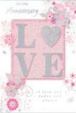 An exquisitely romantic anniversary card fills the frame, its design built around the single, powerful word LOVE, which appears in softly raised letters across the centre. Each letter is coated with a dusting of pale glitter, creating a gentle shimmer in tones of pearl white and silver, as if the word itself has been traced with light. The O subtly hints at a heart shape within its curve, emphasising intimacy without overpowering the design. Behind and around this central motif, the card is awash in muted pastel pinks and silvery greys that blend together like the softest of evening skies over South Tottenham. Delicate flowers unfold around the word, their petals painted in blush, mauve, and ivory tones, some edged with tiny silver highlights. The blooms appear almost watercolor-soft, with fine lines describing each petal and leaf, as though sketched by a florist used to observing every contour of a rose or lisianthus. Wisps of swirling vines, tiny scattered petals, and discreet butterfly shapes add a sense of light movement, giving the impression that the design is gently drifting, not fixed. The background remains smooth and uncluttered, a warm pink canvas that holds the composition together. Elegant script phrases-On Our Anniversary and I love you today and always-are written in slim, flowing letters, mirroring the graceful curves of the illustrated stems. The card's overall feel is one of tender celebration, like a quiet toast shared at home after flowers have been delivered to a doorstep near Downhills Park, honouring a love that has grown deeper with time.